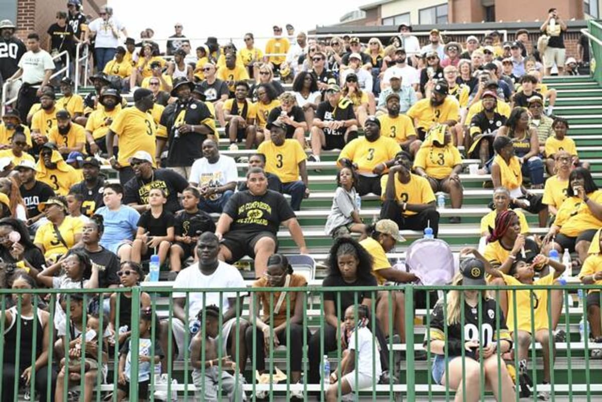 Jaquan Brisker's family members wearing matching yellow jerseys cheering at Steelers practice