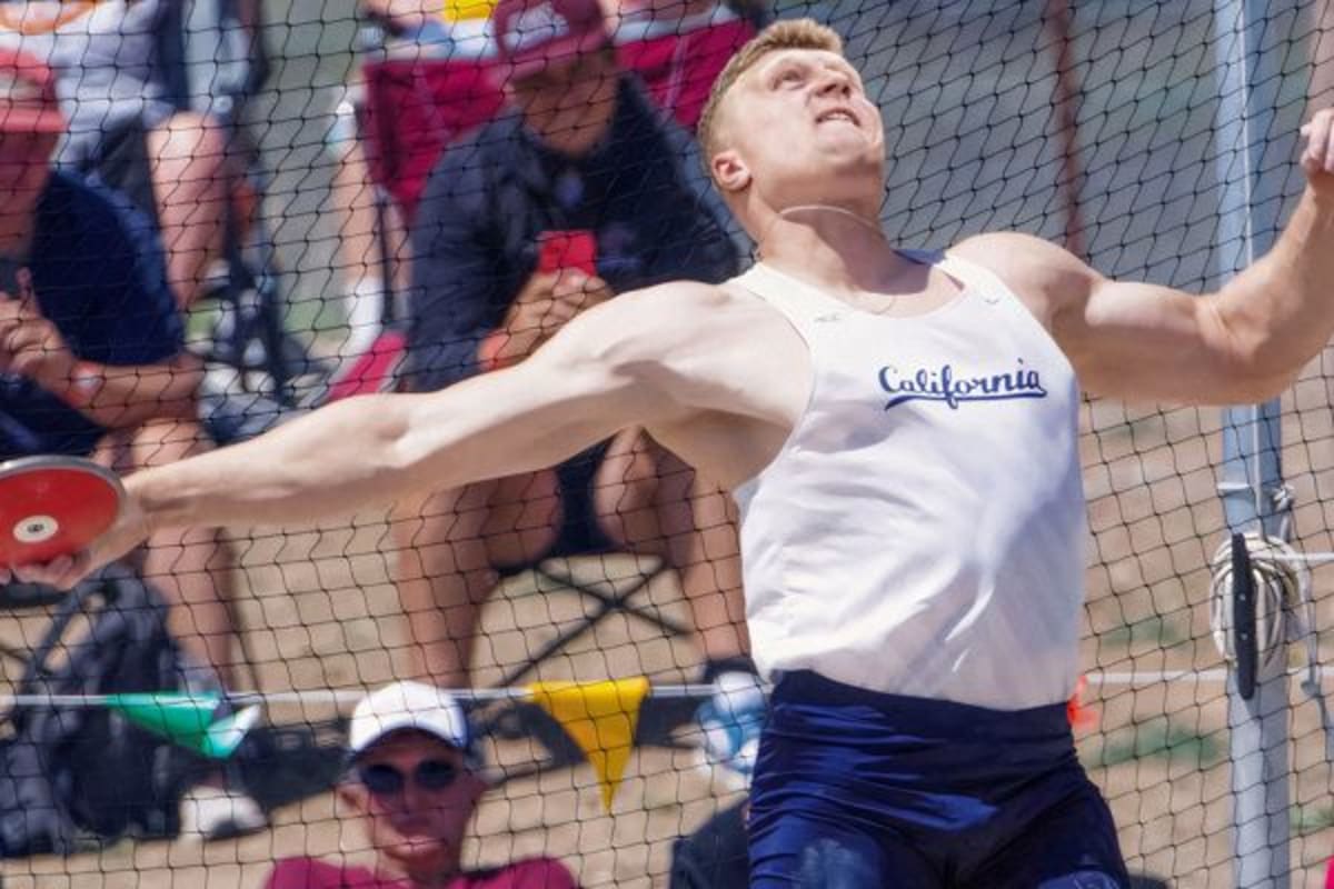 Mykolas Alekna in white Berkeley vest preparing to throw discus at outdoor field