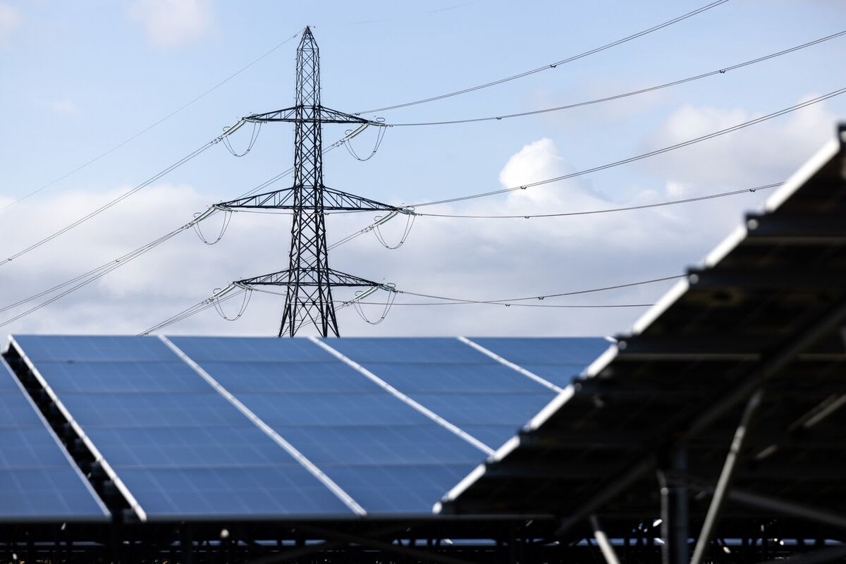 Expansive solar panel farm stretching across green countryside in Lincolnshire, England under blue sky