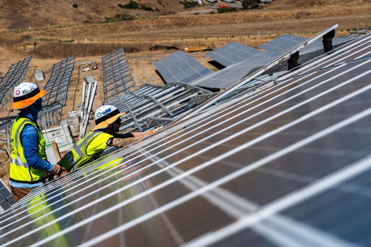 Solar panel installation on rooftop in bright sunlight with workers securing clean energy equipment