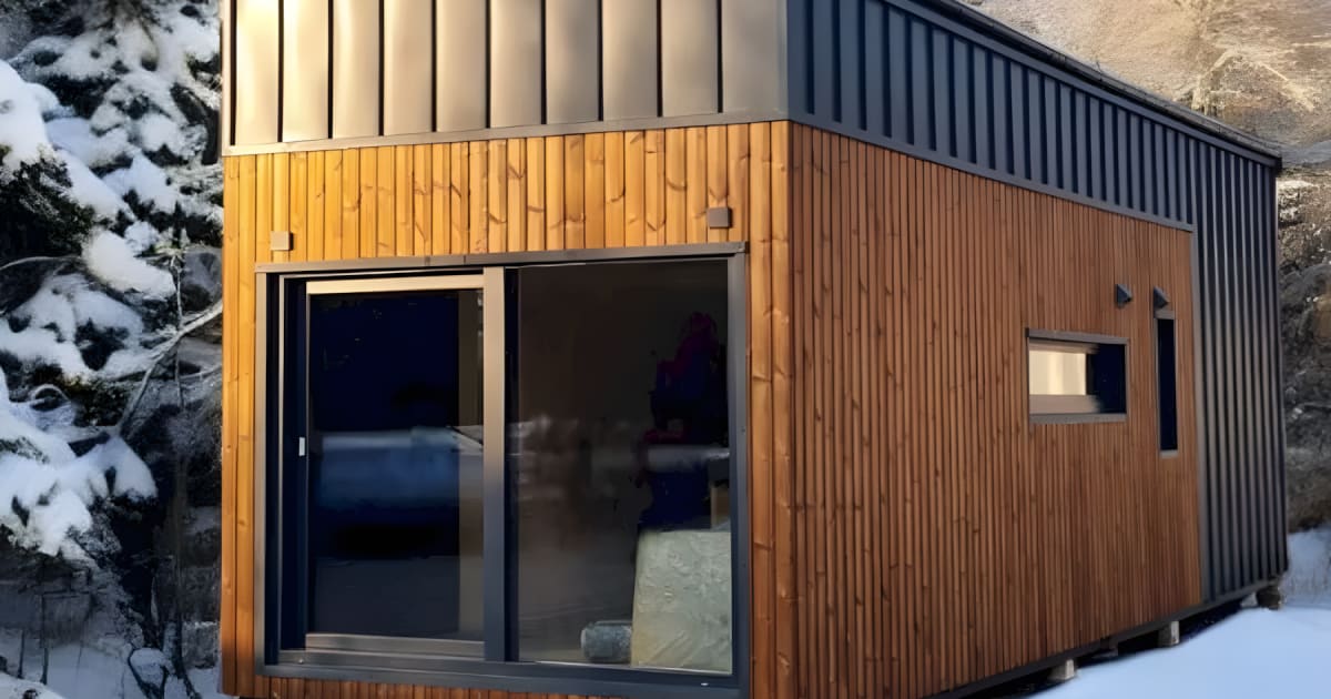 Spacious interior of Samuel tiny house showing high ceilings, glass doors, and wooden finishes