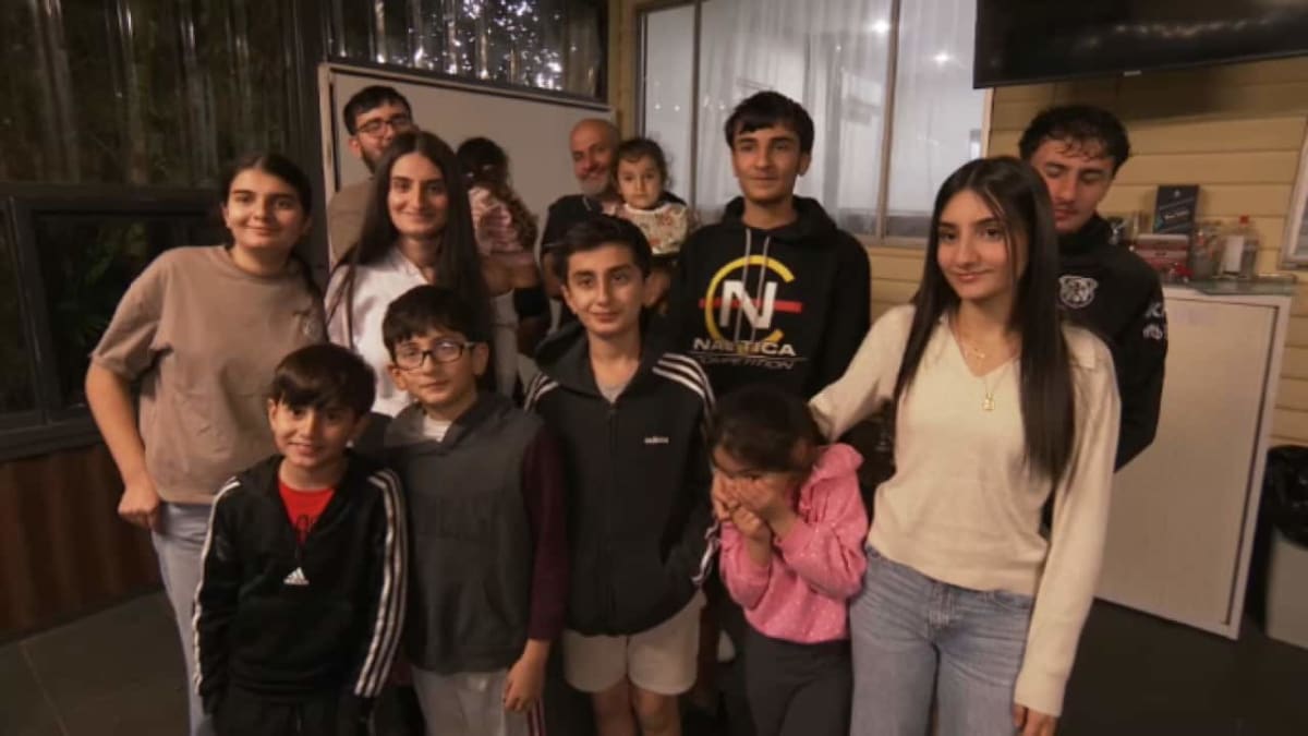 Maria El Khoury smiling with her family of 13 children around dining table
