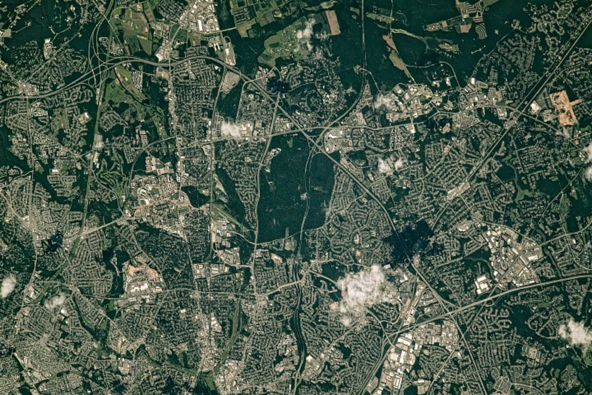 Aerial view from space showing green forests and parks weaving through Maryland suburbs near Washington D.C.