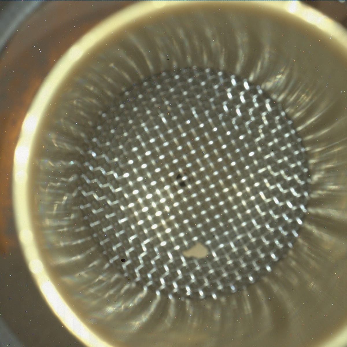 Close-up view of NASA Curiosity rover's CheMin instrument inlet with small rock visible inside