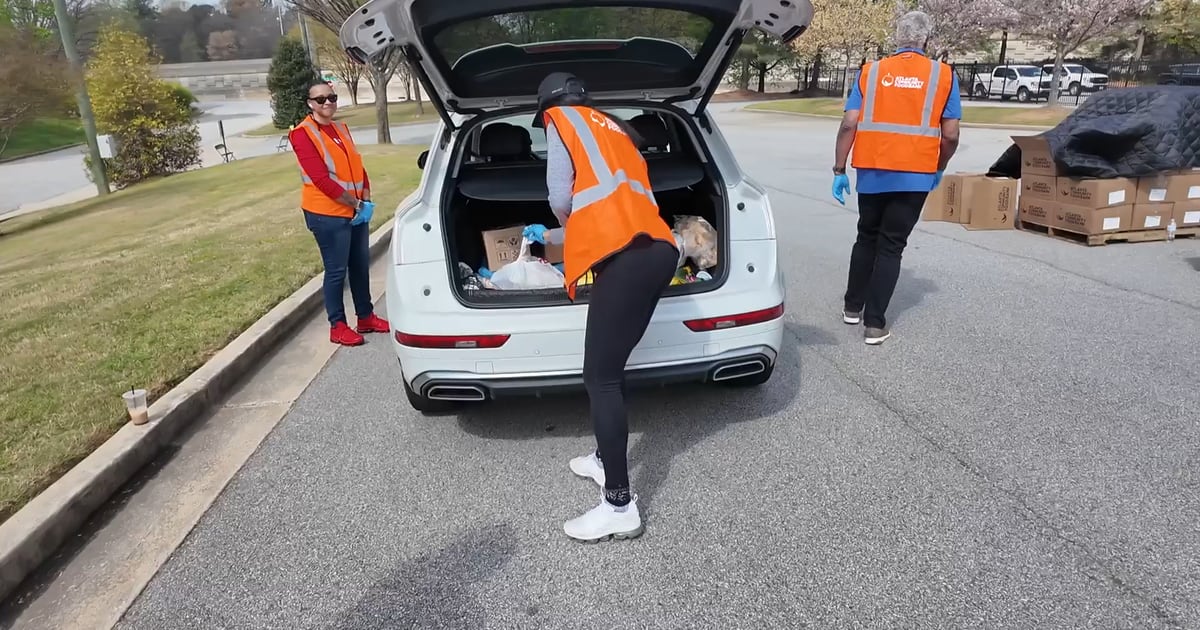Volunteers loading bags of groceries into car trunk at Atlanta airport food distribution