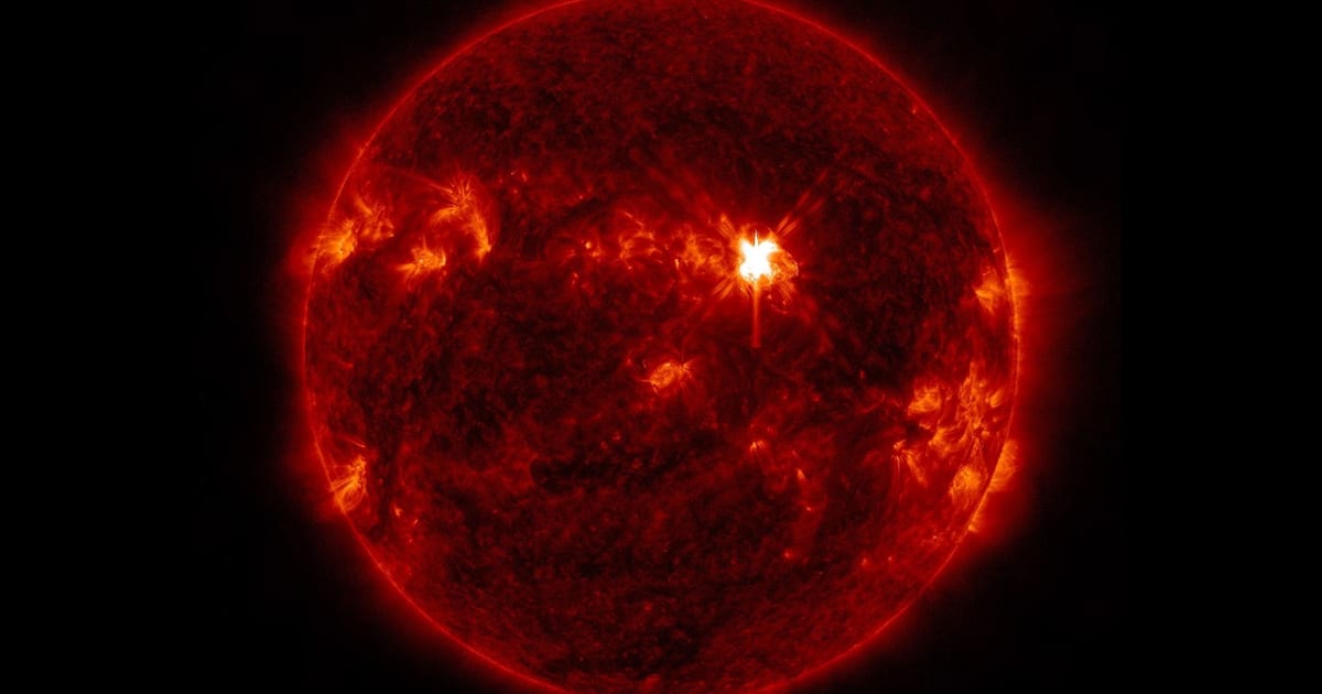 Bright solar flare appearing as flash of light against sun's dark surface captured by NASA