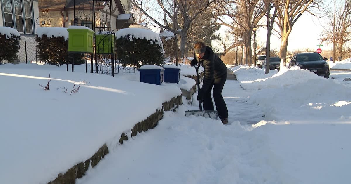 Volunteer shoveling snow from elderly neighbor's driveway during Minnesota winter storm