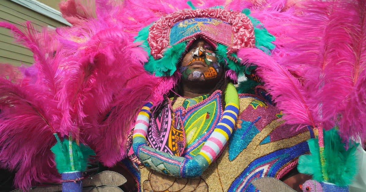 Big Chief in elaborate beaded Mardi Gras Indian suit covered in colorful feathers and rhinestones