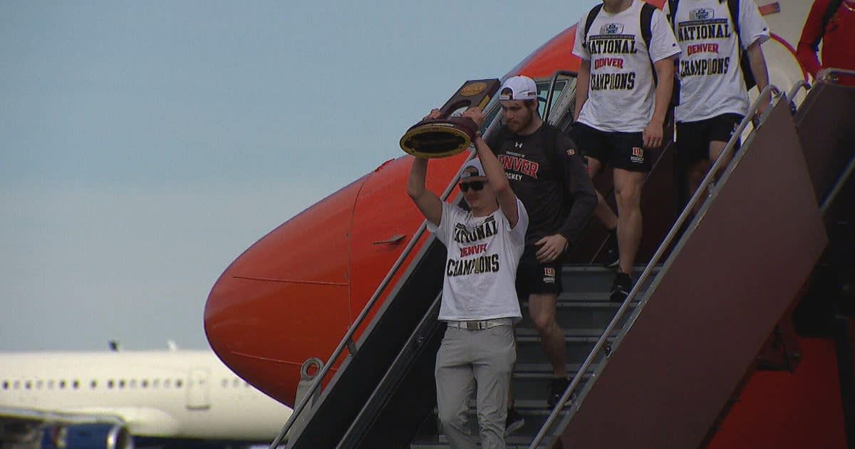 Denver Pioneers hockey team celebrating with national championship trophy at Denver International Airport