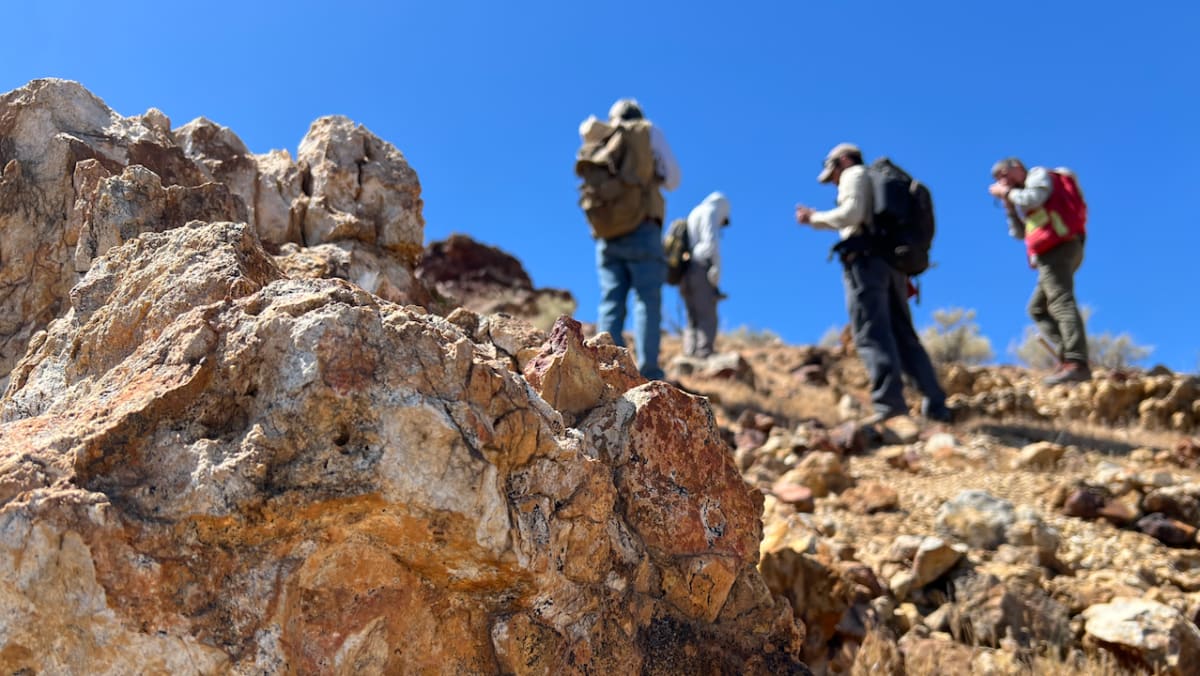 NASA scientists examining red volcanic rocks in California's Mojave Desert during field research mission