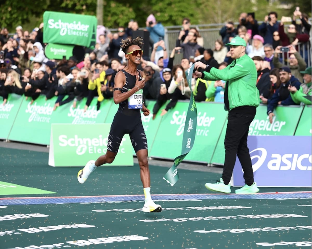 Yeman Crippa crossing finish line at Paris Marathon raising arms in victory celebration