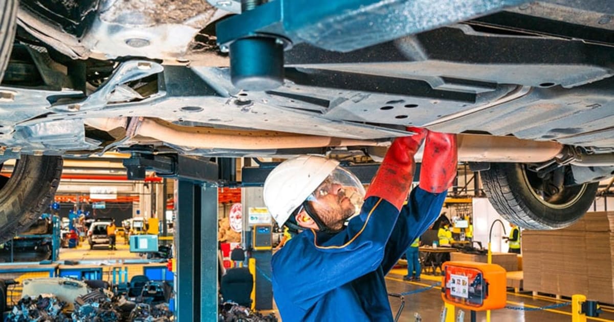 Technician inspecting electric vehicle underside during battery processing for certified reuse program
