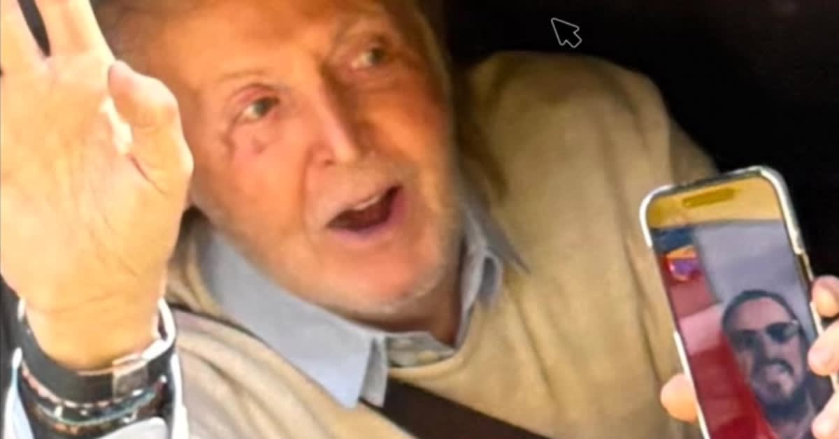 Paul McCartney waving from car window to Beatles tour bus passengers in Liverpool