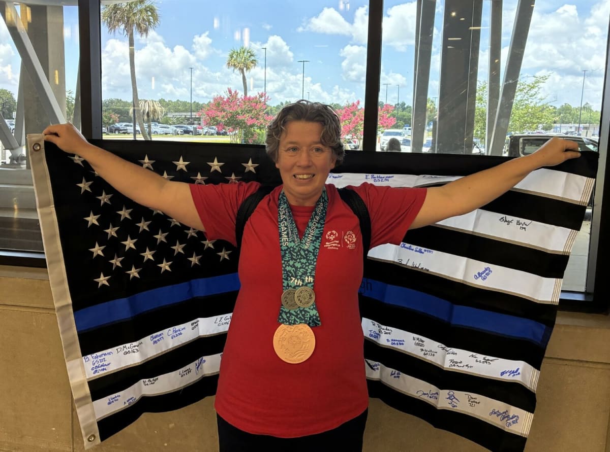 Leigh Anne Landrum smiling while displaying four Special Olympics medals around her neck