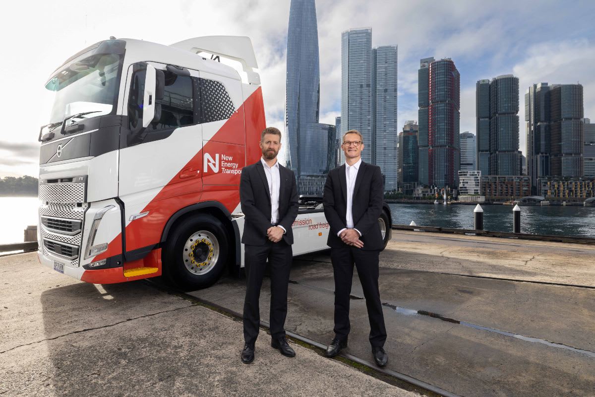 White Volvo electric truck at handover ceremony with executives on Sydney Harbour waterfront