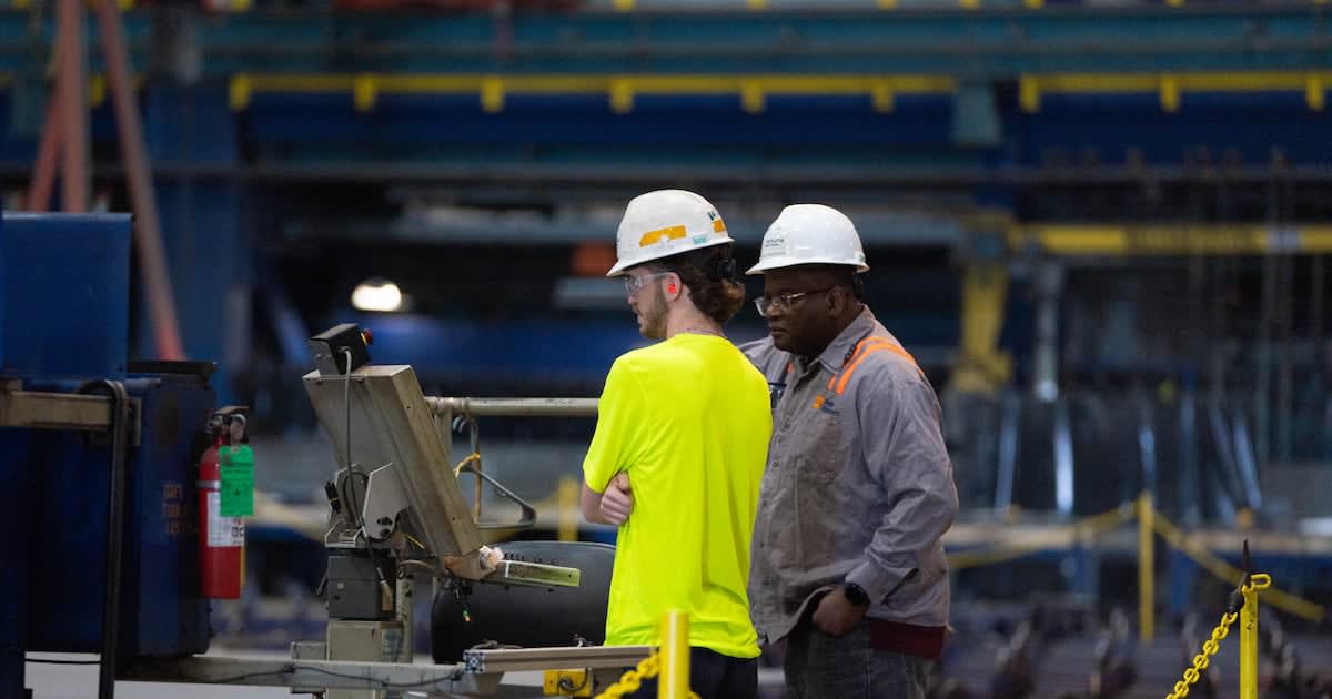 Workers at modern shipbuilding facility with advanced equipment and manufacturing technology