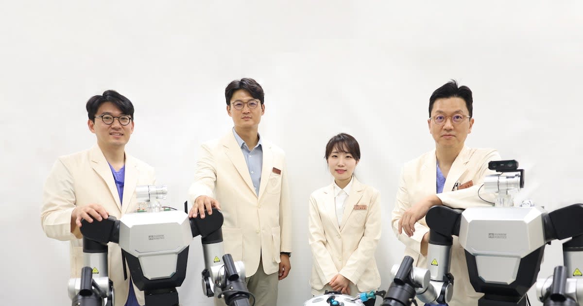 Four Samsung Medical Center researchers in white coats standing together in medical facility discussing surgical robotics project