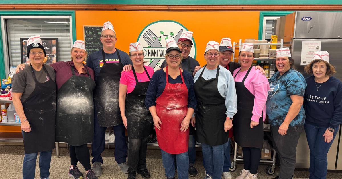 Volunteers in aprons preparing meals together in bright community kitchen workspace