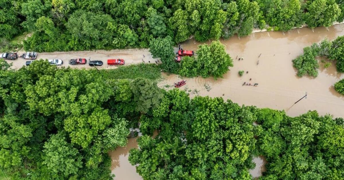 Emergency responders conducting water rescue operation with boat in flooded area near campground