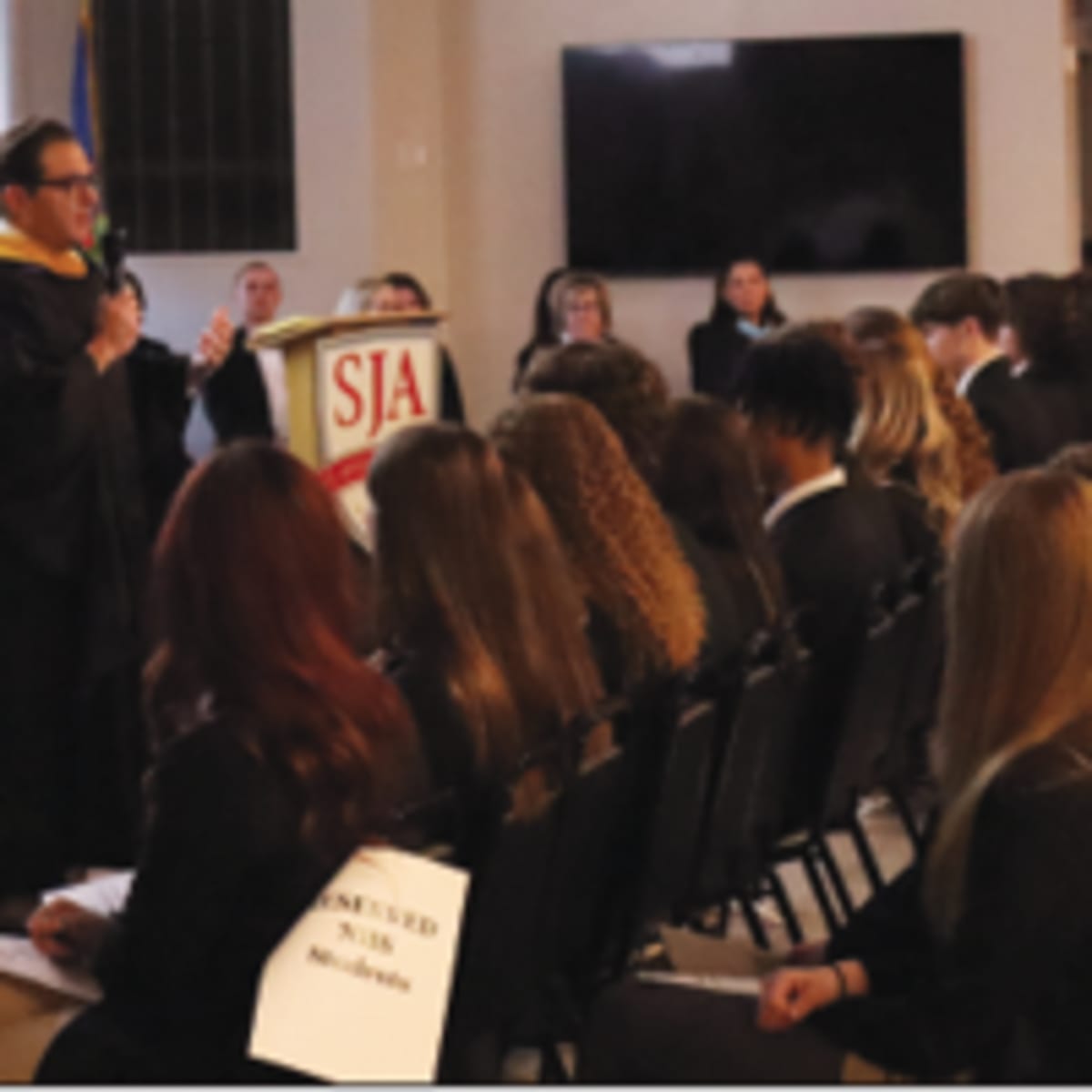 High school students in formal attire at National Honor Society induction ceremony with candles