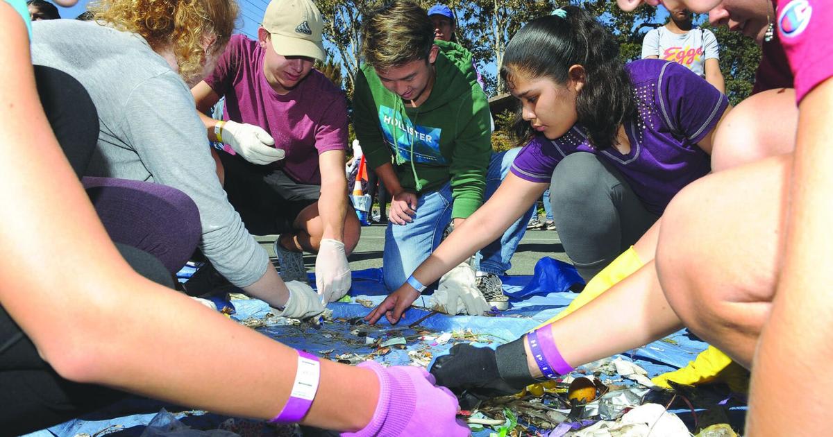 High school students sorting collected trash and recyclables during annual Lodi Lake cleanup event