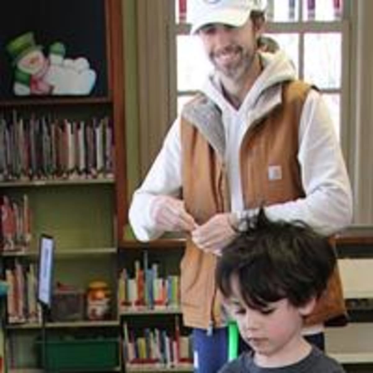 Father and son play miniature golf between bookshelves at library fundraising event