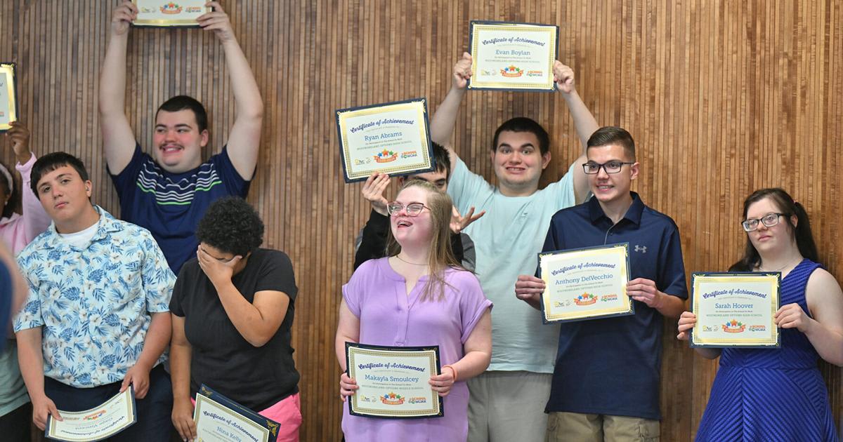 Students from School to Work program holding certificates at graduation ceremony in university library