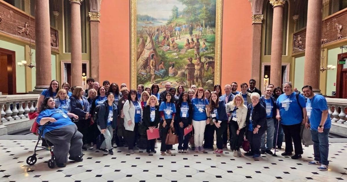 Cancer survivors and advocates wearing suits and sneakers gather at Illinois State Capitol building