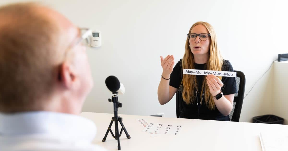 Speech therapy student working with Parkinson's patient through video telehealth session on computer screen