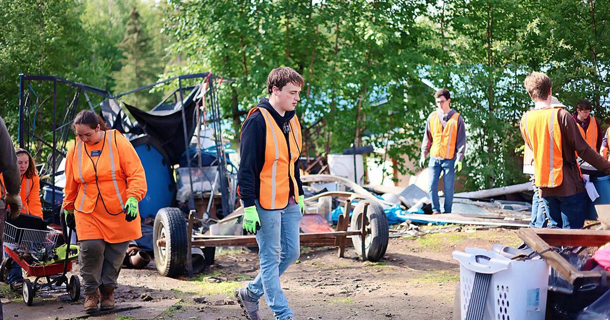 Volunteers working together to clean up an overgrown residential property in Fairbanks, Alaska