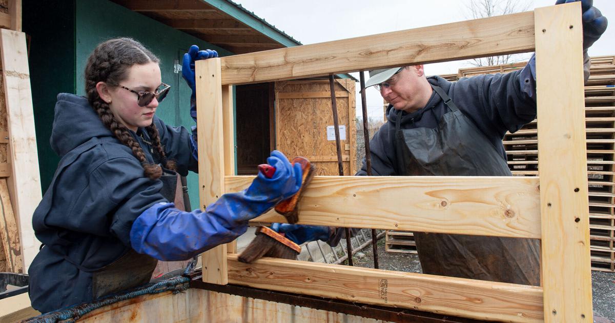 Volunteers in assembly line building wooden bed frames for children in need