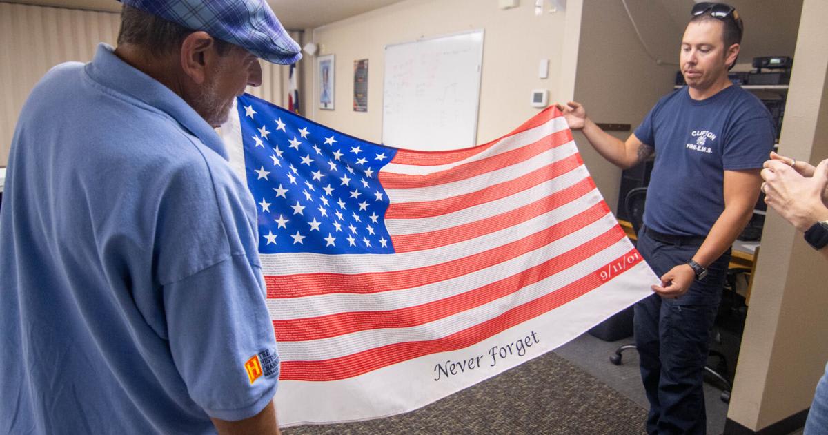 ** Dan Fielding showing firefighter memorial flag with 9/11 victims' names at Colorado fire station