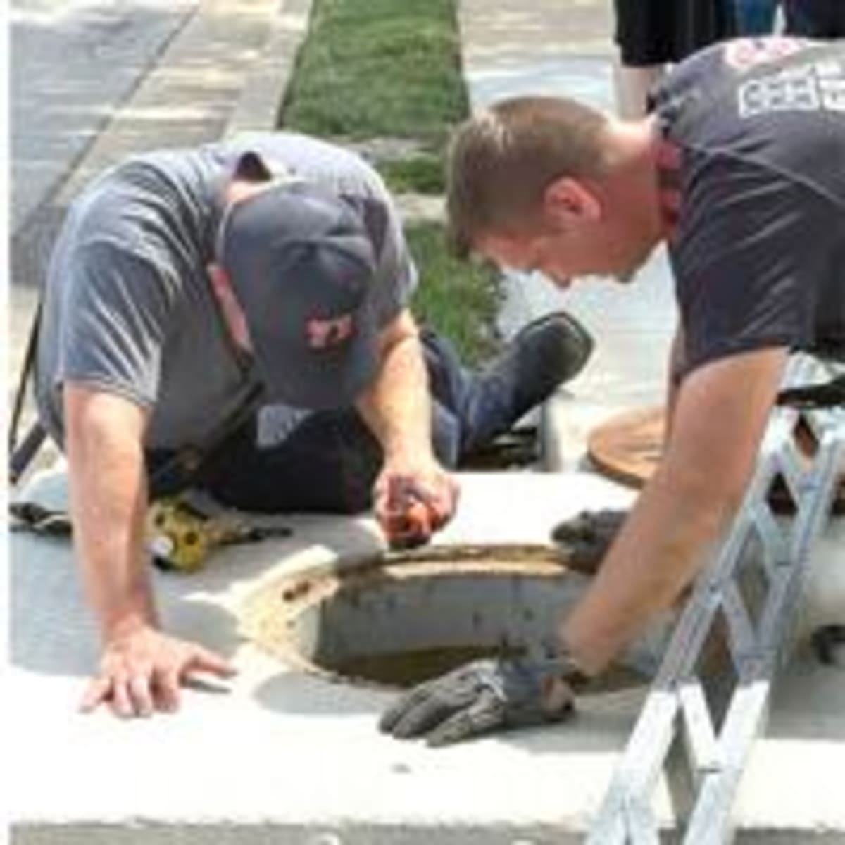 Firefighter climbing into storm drain to rescue ducklings at Arnold shopping plaza