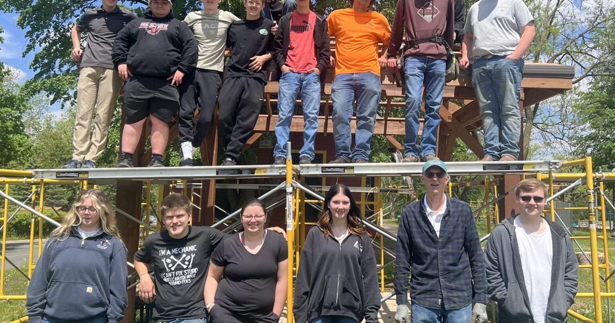 High school students standing beside completed wooden picnic shelter at Minnesota park