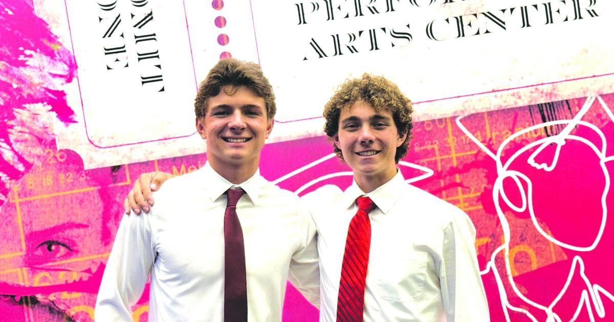 Two high school seniors holding their award for innovative wheel cover design that saves gas