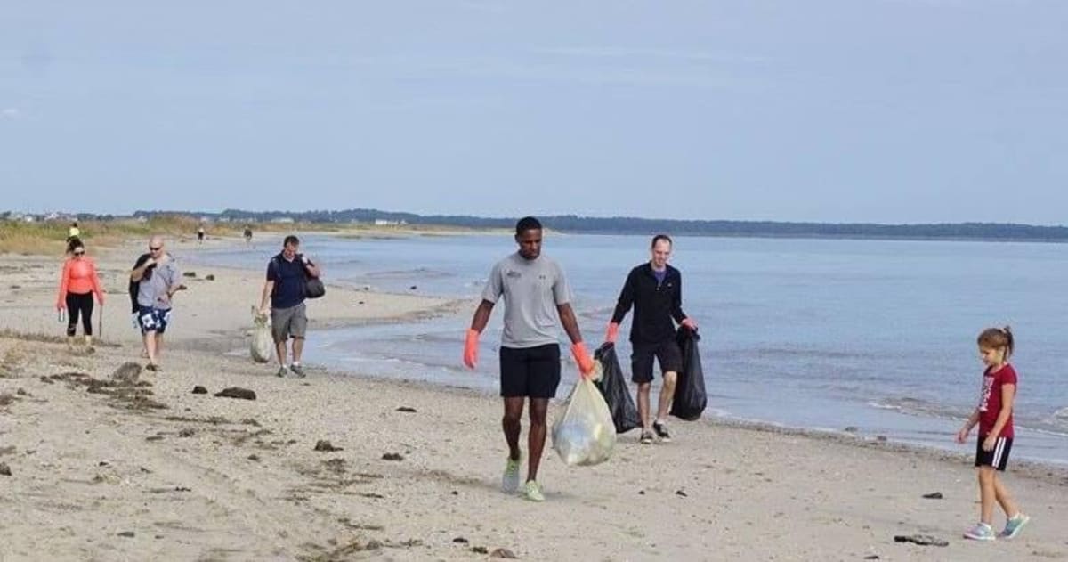 Volunteers collecting litter and debris from Delaware beach during annual coastal cleanup event