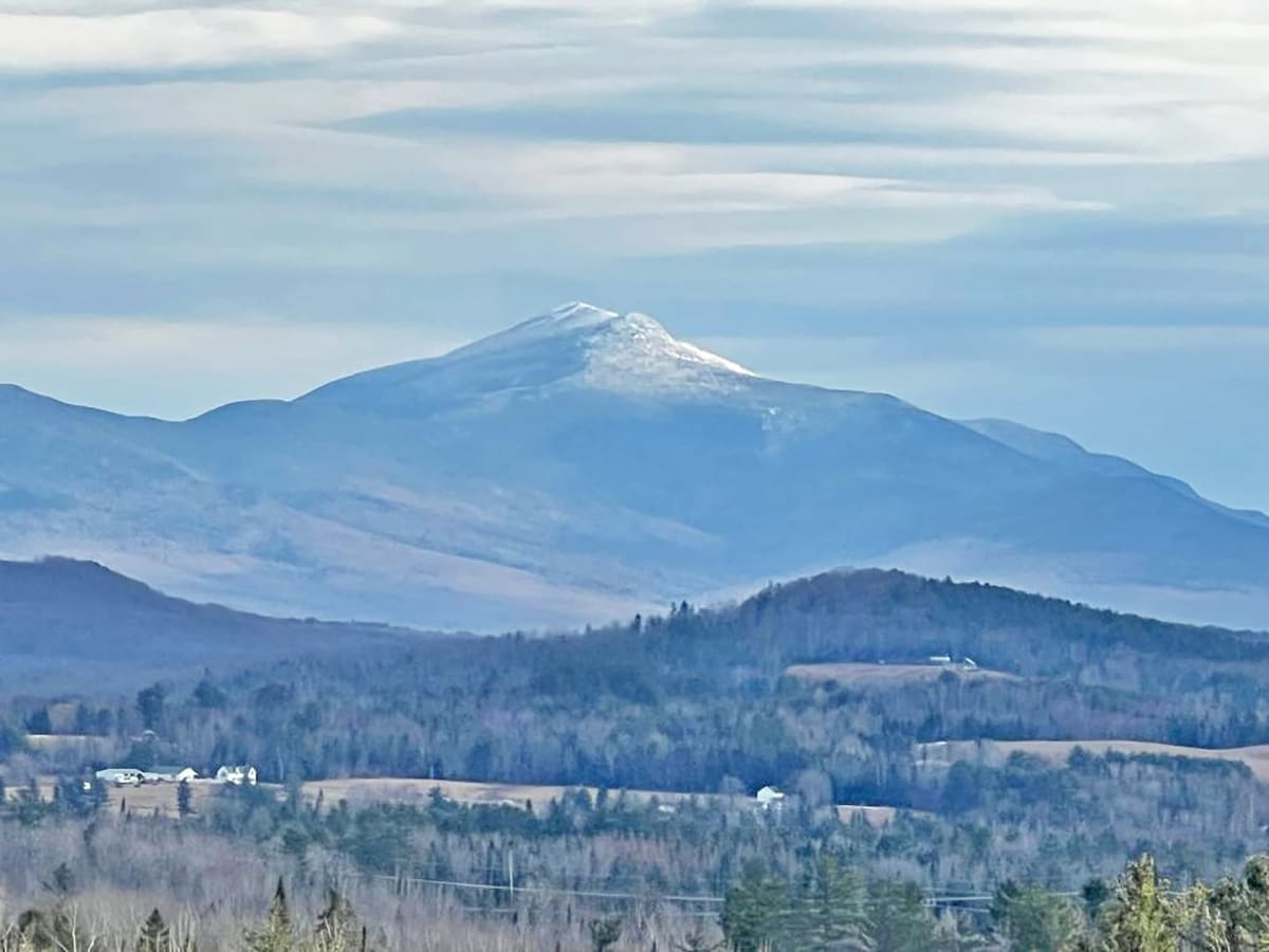 Helicopter flying over forested White Mountains terrain during mountain rescue operation