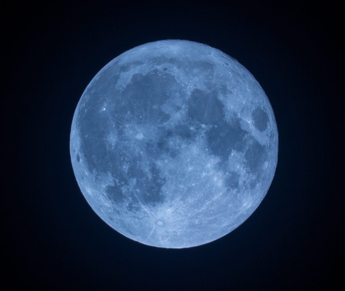 Full moon rising in night sky captured through professional telescope lens