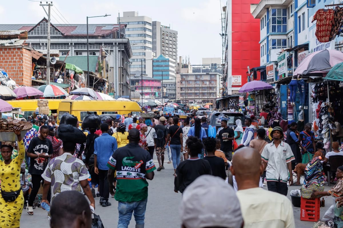 Nigerian person using mobile phone for digital payment transaction in busy market
