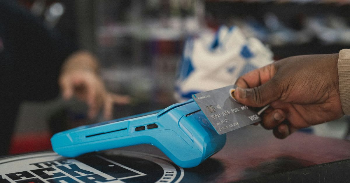 African person using mobile phone for digital payment transaction in busy marketplace