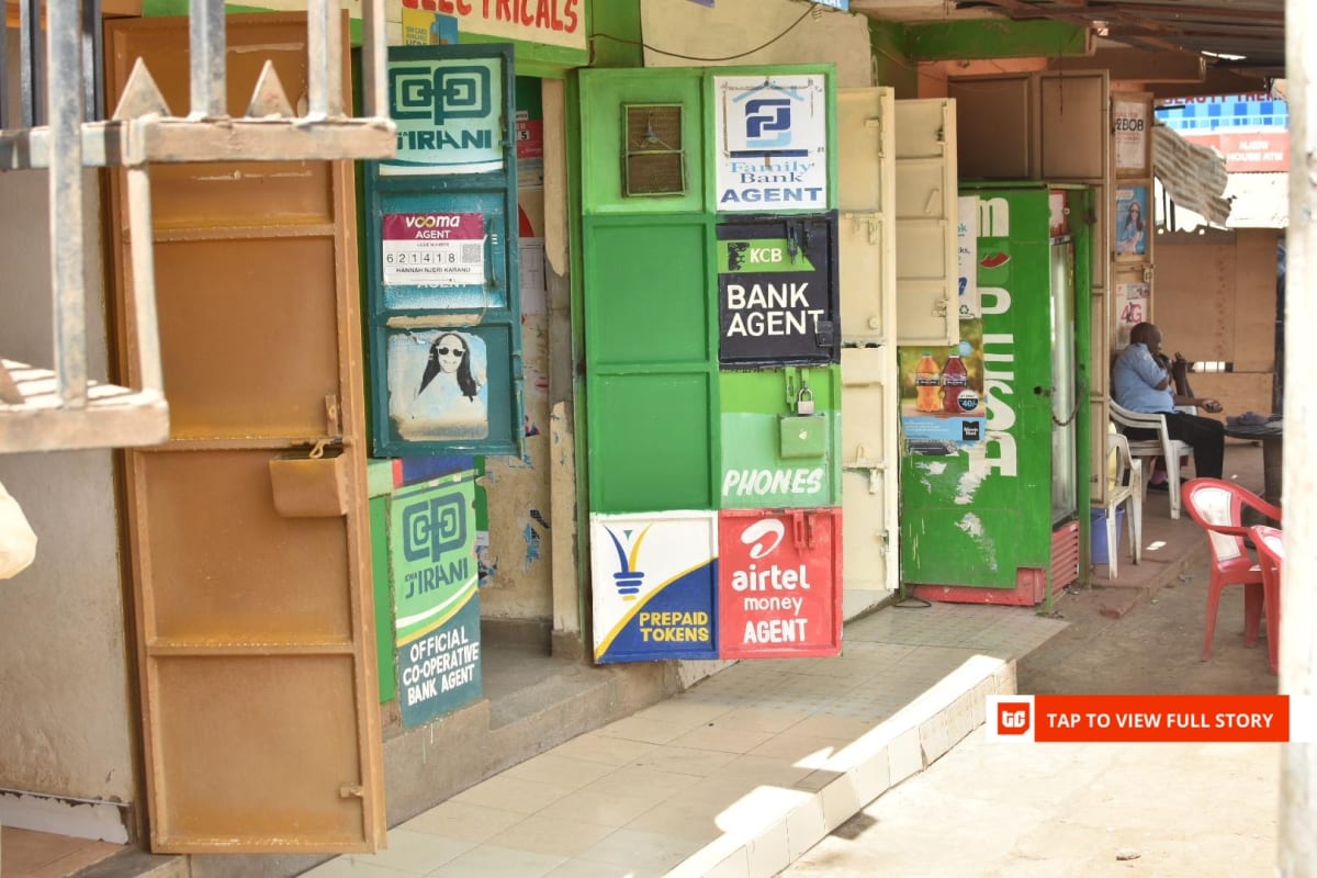 Mobile phone displaying digital payment transaction in busy Kenyan marketplace with vendors