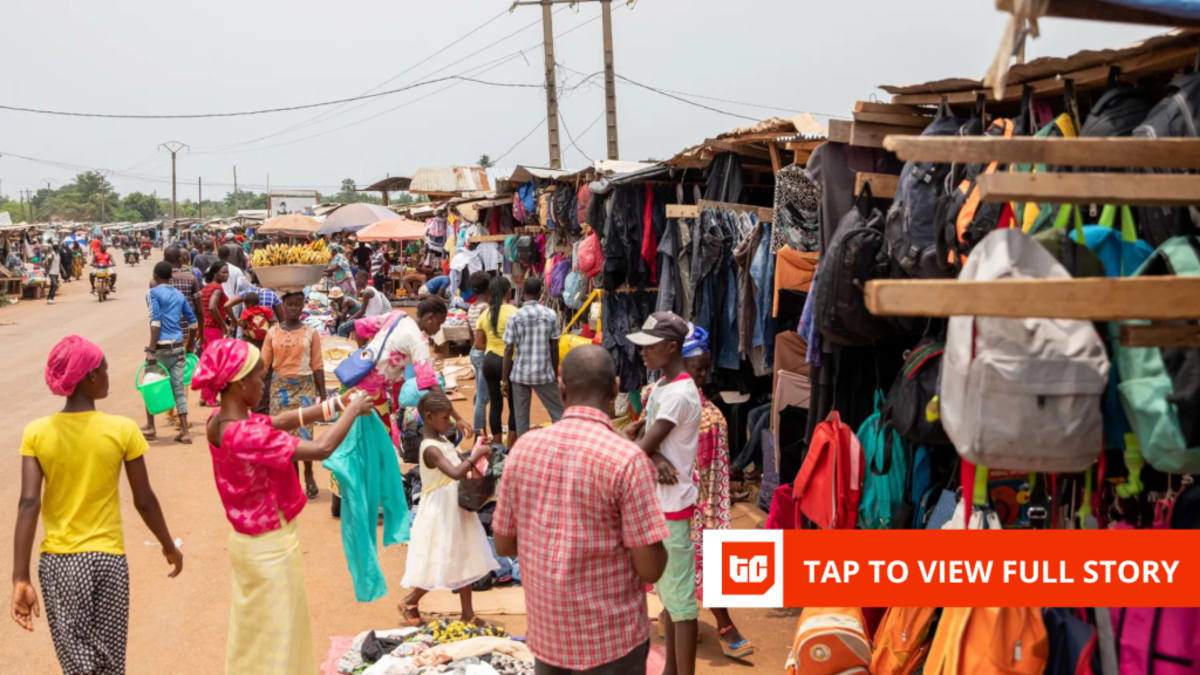 ** Small neighborhood shop owner in West Africa using smartphone for digital business transactions