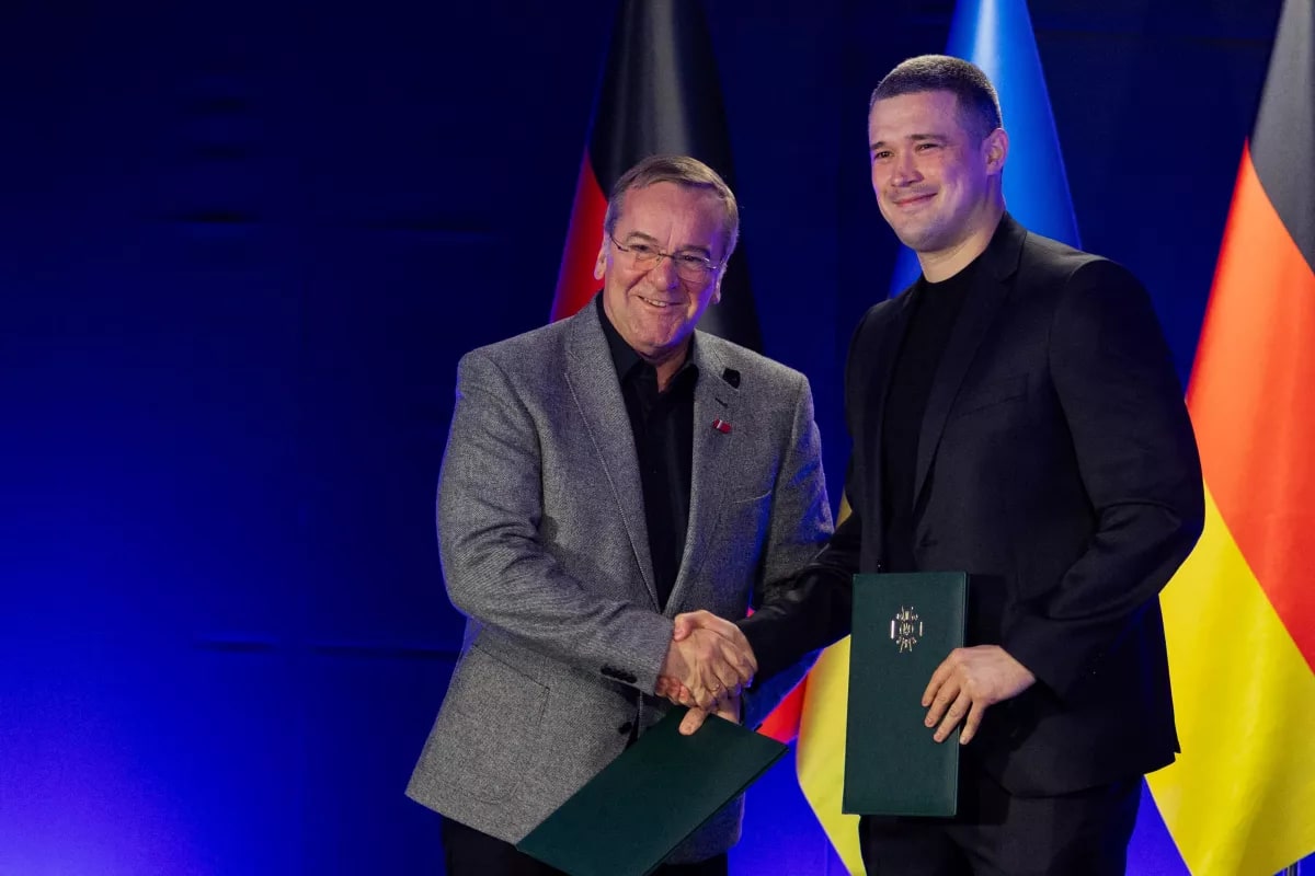 German and Ukrainian officials shaking hands at defense technology partnership announcement in Kyiv