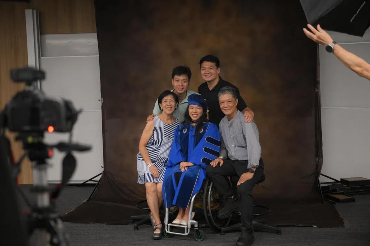 Yip Pin Xiu in academic regalia receiving honorary doctorate from SMU chancellor, surrounded by family
