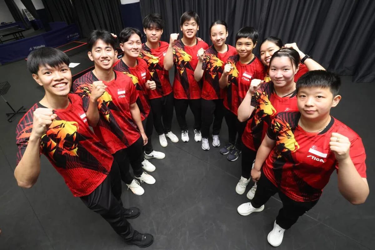 Ten young Singapore table tennis players posing together with paddles before Asian Games competition