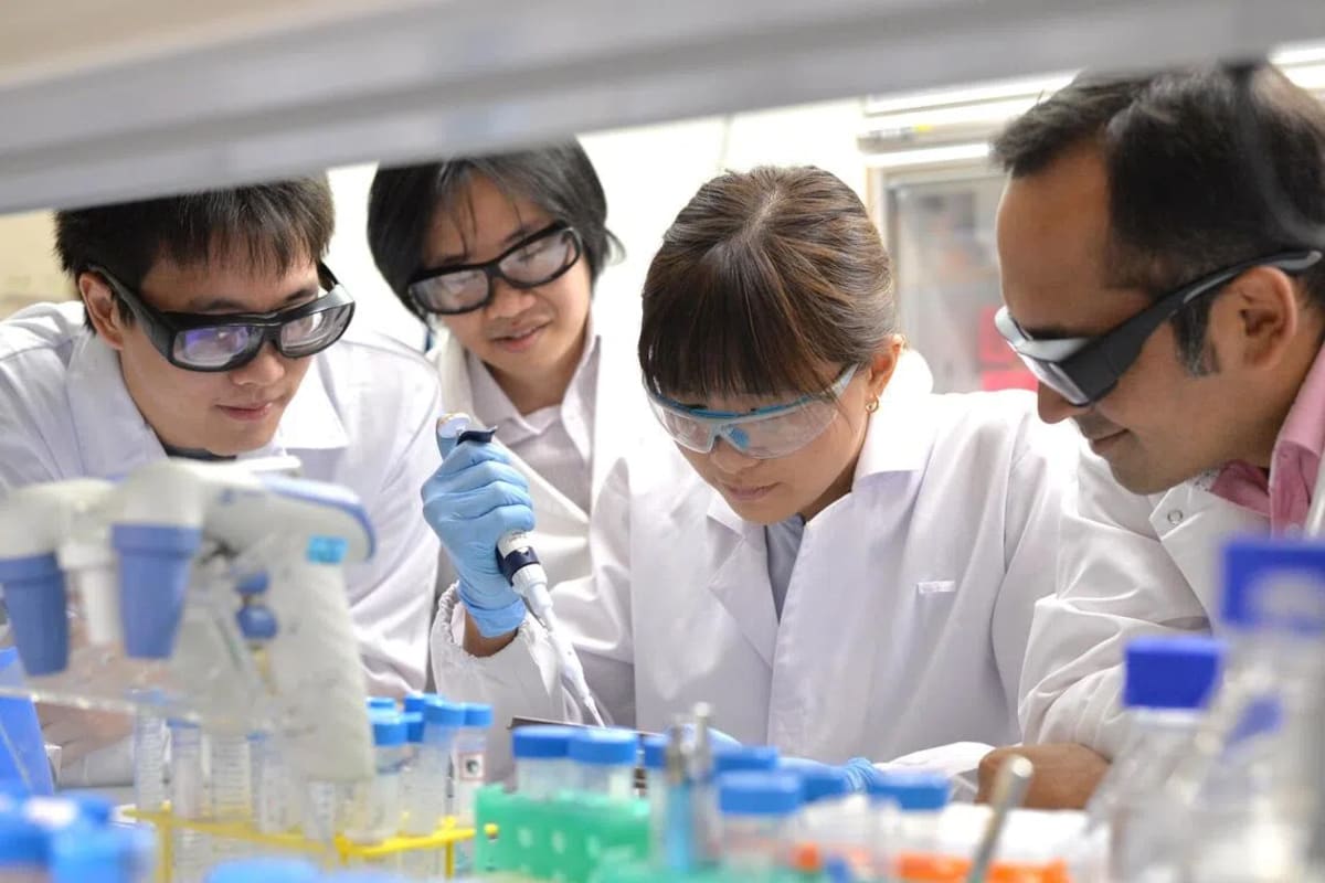 Dr. Glenn Bonney standing with research team members at National University of Singapore laboratory
