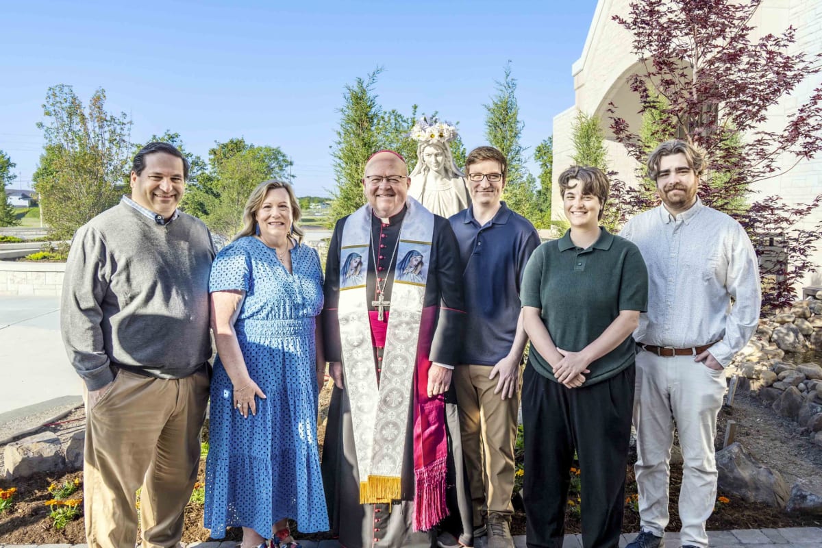 Nastars family stands with Bishop Kemme beside marble Our Lady of Grace statue at Wichita church