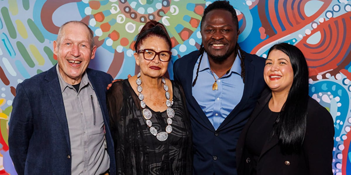 Large diverse crowd gathered at formal dinner with Indigenous cultural performers on stage