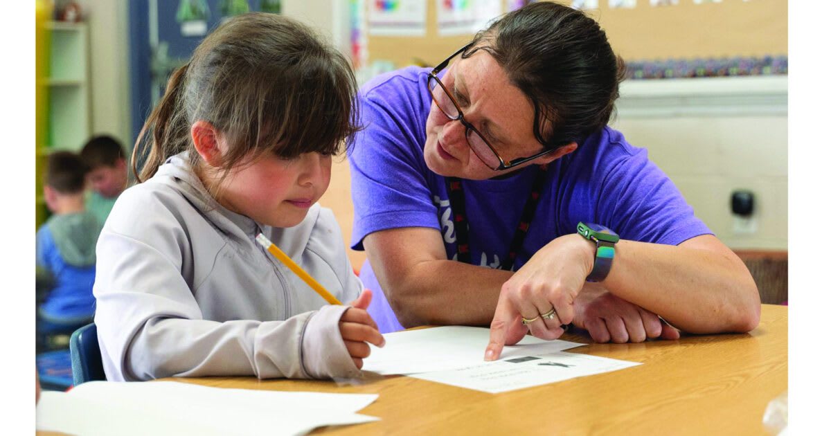 Kindergarten teacher Heather Little helps young student with classroom work at Little Flower School