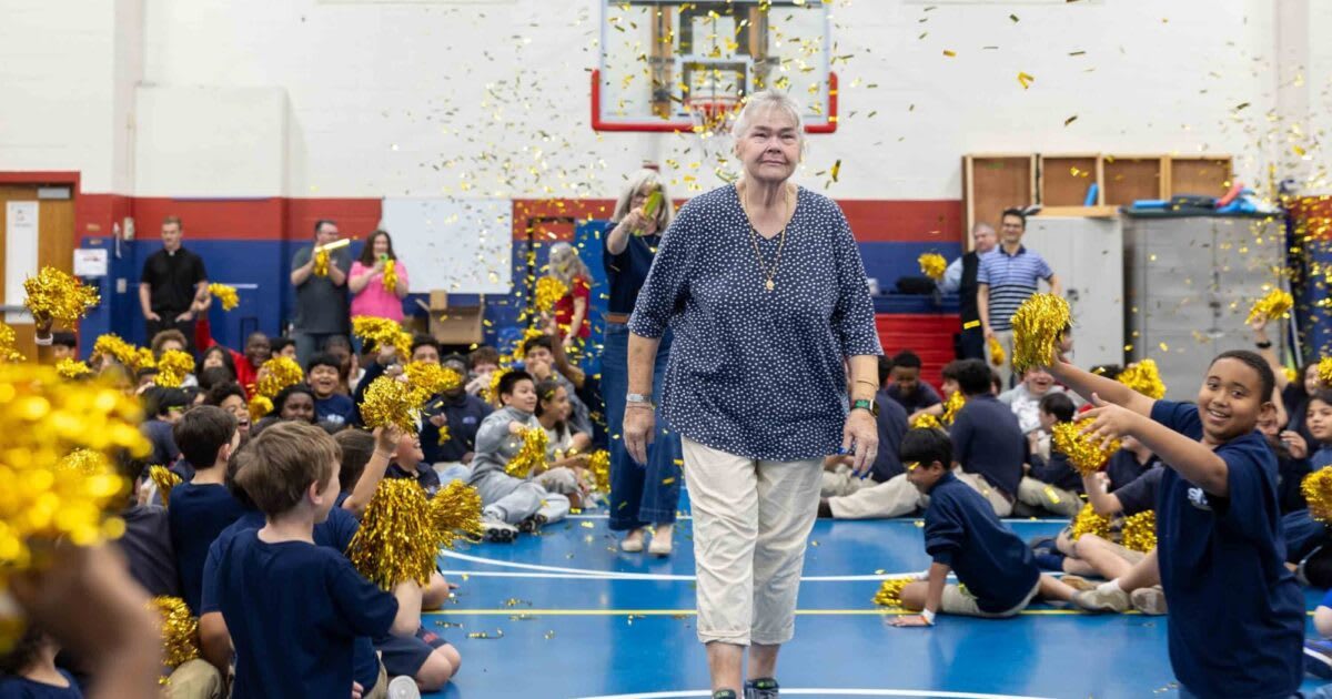 Teacher Julie Stinger embraces her adult daughter during surprise award ceremony at school